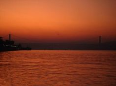 the sun is setting over the water and bridge