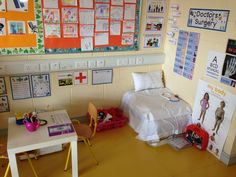 a room with desks, chairs and posters on the wall above it is a bed