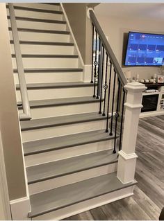 a white stair case next to a flat screen tv