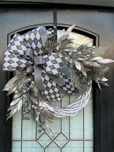 a wreath with silver and black decorations hanging on the front door to give it a festive touch