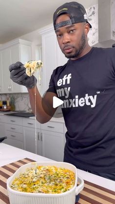 a man in a black shirt is holding up a piece of food and looking at the camera