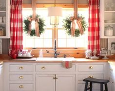 the kitchen is decorated for christmas with wreaths on the windowsill and plaid curtains