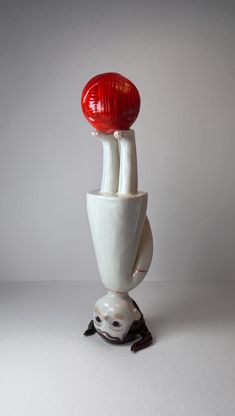 two white vases with red and black objects on top of each other, one is upside down