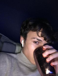 a young man drinking from a cup in the dark