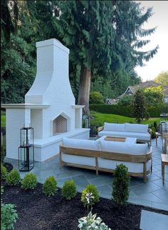 an outdoor living area with couches, tables and a fire place in the middle