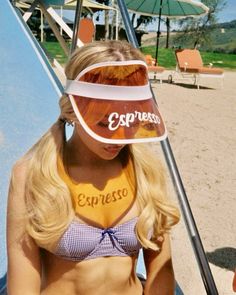 a woman wearing a hat with the word espresso on it sitting next to a surfboard