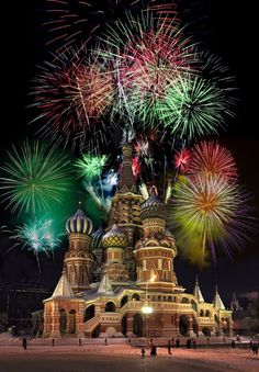 fireworks are lit up in the night sky above a building with towers and spires