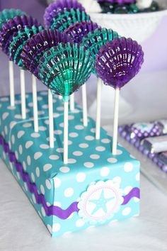 purple and green lollipops are sitting on top of a blue gift box