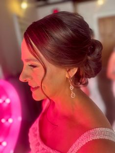 a woman in a pink dress is smiling at something with bright lights on the wall behind her