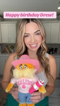 a woman holding a stuffed animal wearing a pink hat and name on it's shirt