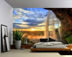 a bedroom with a waterfall in the background and a sunset on the wall behind it