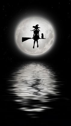 a black and white photo of a witch on a broom flying over the water at night