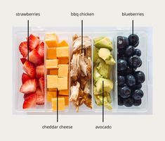 a plastic container filled with different types of fruits and vegetables next to cheese, strawberries, blueberries, and avocado