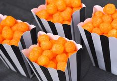 four black and white striped paper bags filled with orange candies on top of a table