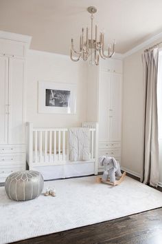 a baby's room with white furniture and chandelier