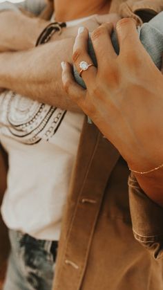 a man wearing a ring and jacket with his arm wrapped around the woman's shoulder