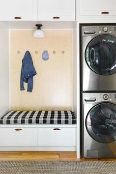 a washer and dryer in a small room with white cabinets, black and white checkered bench