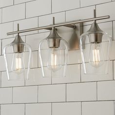 three light fixtures mounted on a white brick wall