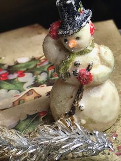 a snowman made out of fruit sitting on top of a tinsel covered table