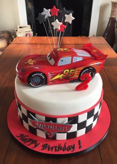 a birthday cake with a red race car on top and stars in the air above it