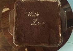 a chocolate cake with writing on it sitting on top of a wooden table next to a glass plate