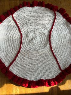 a crocheted red and white doily sitting on top of a wooden floor