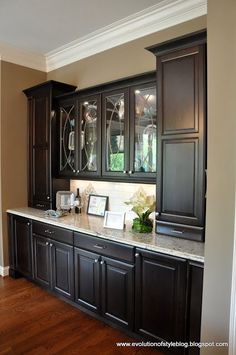 an empty kitchen with dark wood cabinets and marble counter tops, along with hardwood flooring