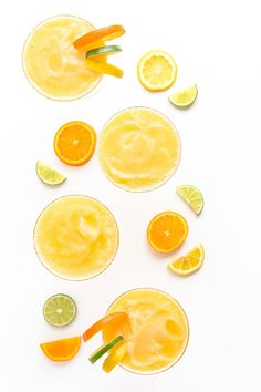 several glasses filled with orange juice and garnished with slices of lemon, carrots, and lime