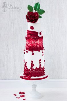 a white and red wedding cake with roses on top