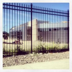 an image of a building through the bars of a fenced in area with rocks and grass