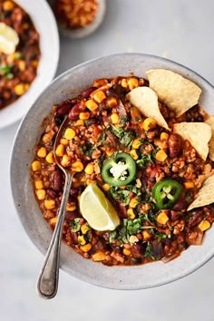 a bowl filled with chili, corn and tortilla chips on top of a table