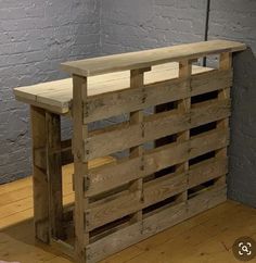 a wooden bench sitting on top of a hard wood floor next to a brick wall