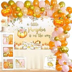 an orange and gold balloon arch for a baby's first birthday party with pumpkins