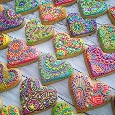 many decorated heart shaped cookies sitting on top of a wooden table next to each other