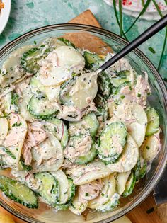 a glass bowl filled with cucumber salad on top of a wooden cutting board