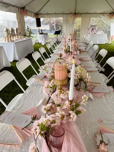 a long table set up with pink flowers and candles for an outdoor wedding or reception