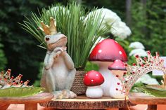 a table topped with figurines and plants on top of wooden tables in front of trees