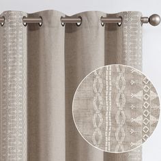 a curtain with an embroidered design on it and a round medallion hanging from the rod