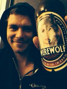 a man holding up a bottle of beer with a wolf on the front and side