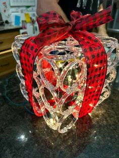 a red and black bow sitting on top of a glass container filled with christmas lights