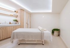 a white room with a bed, sink and plants on the counter top next to it