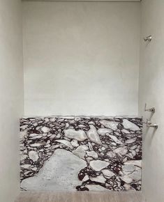 an empty bathroom with white walls and marble flooring