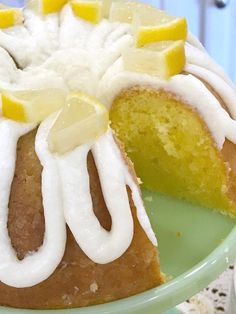 a cake with white frosting and lemon slices on top is sitting on a green plate