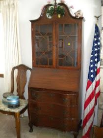 an old wooden china cabinet sitting next to a flag on a table in a living room