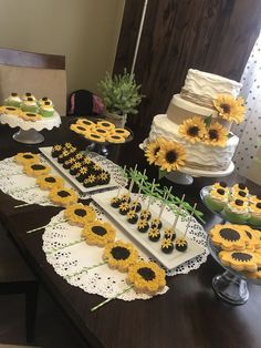 a table topped with lots of cakes and cupcakes covered in sunflowers