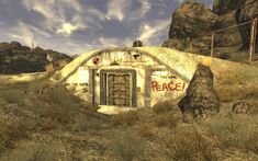 an old building with graffiti on it in the middle of a desert area next to some rocks