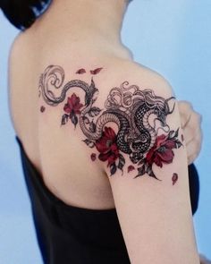 a woman with a dragon and flowers tattoo on her shoulder, holding onto the arm