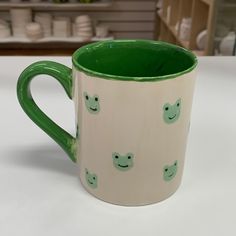 a green and white coffee mug with smiley faces on it