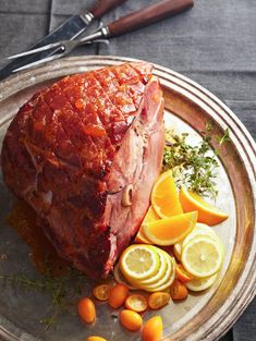 a large piece of meat sitting on top of a plate next to sliced oranges