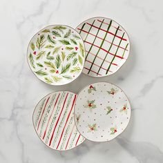 three plates with christmas designs on them sitting on a marble surface